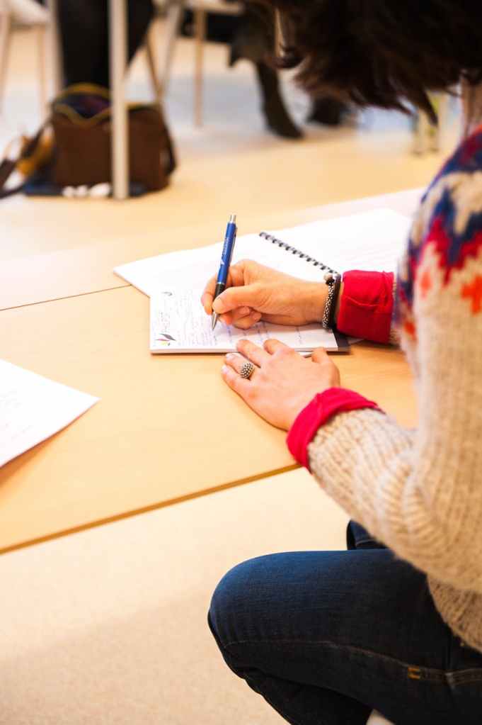 woman holding blue pen writing on paper