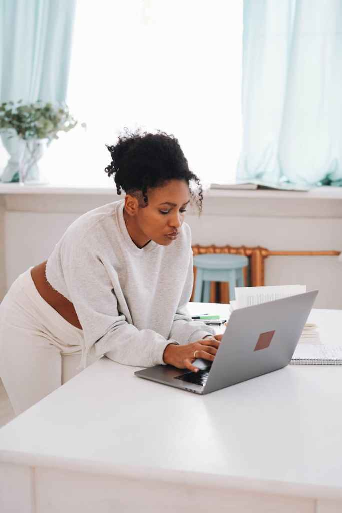 woman in white sweater using a laptop at home